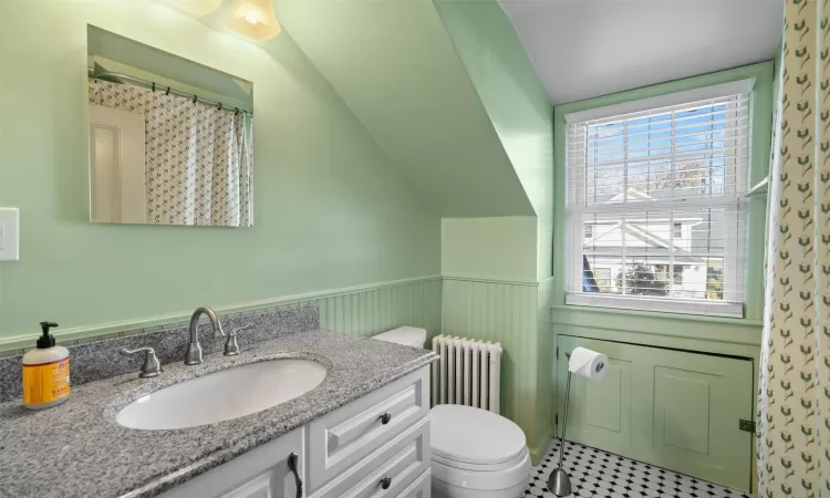 Bathroom with toilet, vaulted ceiling, a shower with curtain, vanity, and radiator heating unit