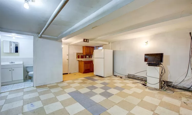 Basement featuring sink and white fridge