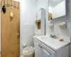 Bathroom featuring tile walls, toilet, and vanity