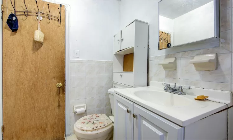 Bathroom featuring tile walls, toilet, and vanity