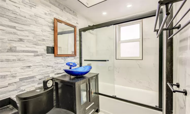 Full bathroom with toilet, vanity, and shower / bath combination with glass door