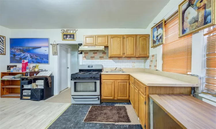 Kitchen featuring gas range, sink, backsplash, and hardwood / wood-style floors