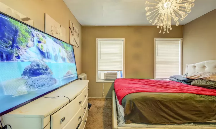 Bedroom with cooling unit, a notable chandelier, and carpet flooring