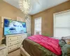 Carpeted bedroom featuring cooling unit, radiator, and a notable chandelier