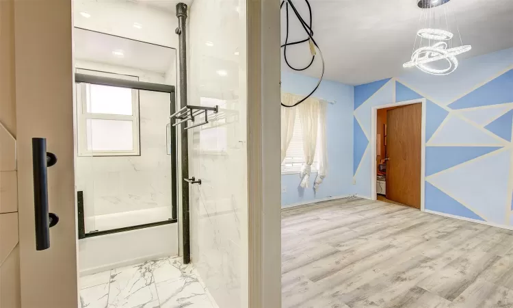 Bathroom with enclosed tub / shower combo and a chandelier