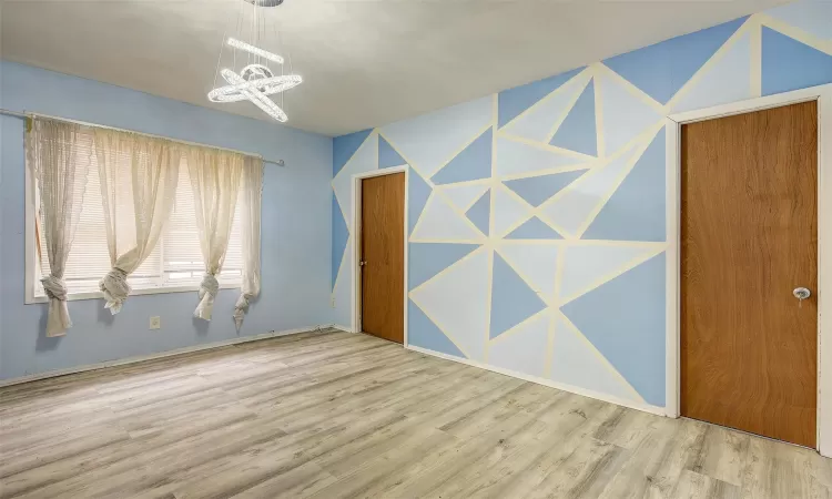 Spare room featuring wood-type flooring and a notable chandelier