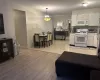 Kitchen with decorative light fixtures, white cabinets, white appliances, and light hardwood / wood-style flooring