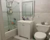 Full bathroom featuring toilet, combined bath / shower with glass door, tile walls, and vanity