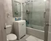 Full bathroom with toilet, combined bath / shower with glass door, tile patterned flooring, tile walls, and vanity