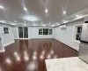 Basement featuring an AC wall unit, a baseboard radiator, stainless steel fridge, and dark wood-type flooring