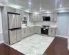 Kitchen featuring exhaust hood, backsplash, gray cabinets, sink, and stainless steel appliances