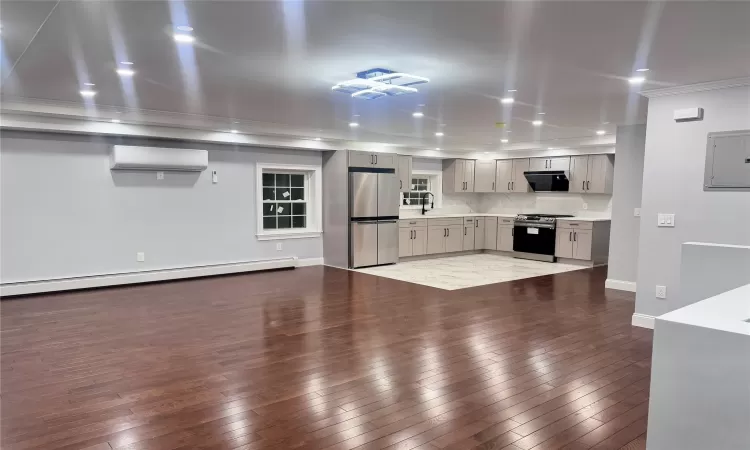 Kitchen featuring an AC wall unit, a baseboard radiator, appliances with stainless steel finishes, electric panel, and gray cabinetry