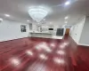 Unfurnished living room with a baseboard heating unit, ornamental molding, a chandelier, and hardwood / wood-style floors