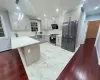 Kitchen featuring backsplash, kitchen peninsula, light stone countertops, appliances with stainless steel finishes, and a baseboard radiator