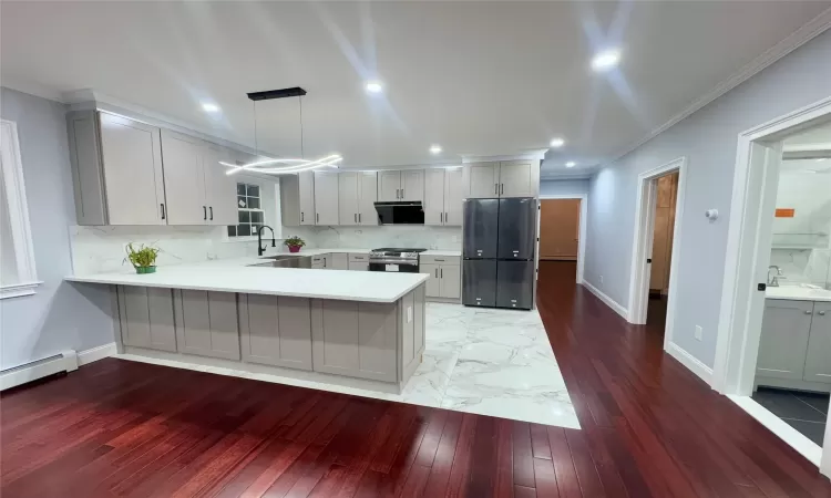 Kitchen with gas stove, black fridge, kitchen peninsula, sink, and hanging light fixtures