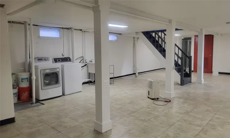 Basement with light tile patterned flooring and washer and dryer