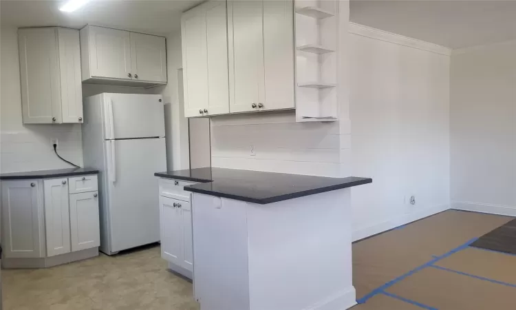 Kitchen with backsplash, white cabinets, ornamental molding, and white fridge