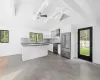 Kitchen featuring wall chimney exhaust hood, beamed ceiling, high end appliances, and white cabinetry