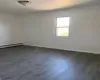 Spare room featuring dark wood-type flooring and a baseboard heating unit