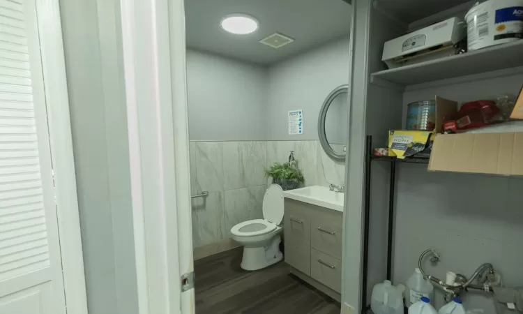 Bathroom with tile walls, toilet, vanity, and hardwood / wood-style floors