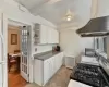 Kitchen with sink, white cabinets, beamed ceiling, and stove