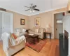 Living room featuring ceiling fan, light wood-type flooring, a fireplace, and crown molding