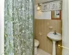 Bathroom with toilet, tile walls, tile patterned flooring, and a shower with curtain