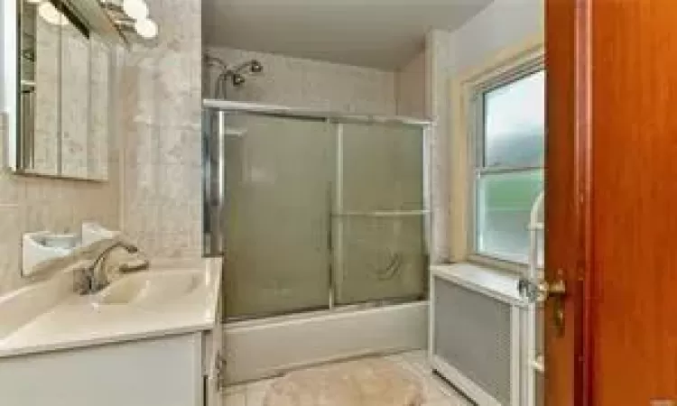 Bathroom featuring vanity and shower / bath combination with glass door