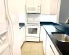 Kitchen featuring white cabinetry, sink, and white appliances