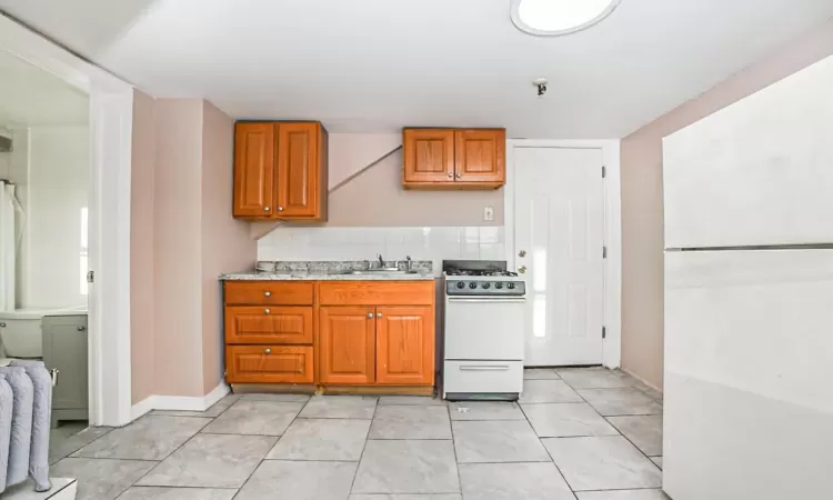 Kitchen with white appliances, tasteful backsplash, light tile patterned flooring, and sink