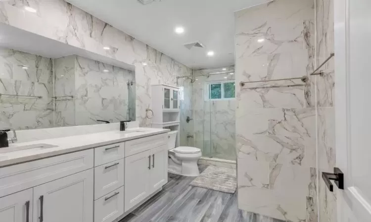 Bathroom featuring an enclosed shower, vanity, tile walls, hardwood / wood-style floors, and toilet