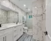 Bathroom featuring vanity, toilet, walk in shower, tile walls, and wood-type flooring