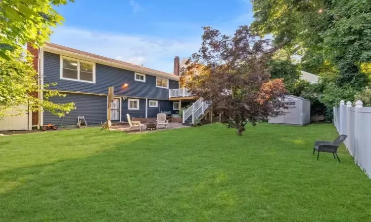 Rear view of house featuring a lawn, an outdoor fire pit, a patio area, and a storage unit