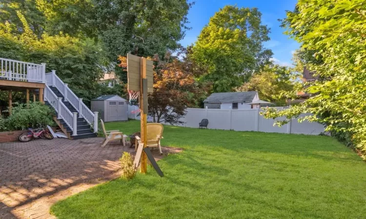 View of yard with a storage shed, a patio area, and a wooden deck