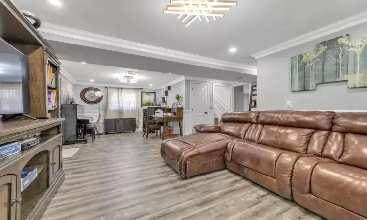 Living room featuring an inviting chandelier, light hardwood / wood-style flooring, and crown molding