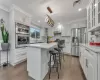 Kitchen with pendant lighting, a center island, ornamental molding, white cabinetry, and stainless steel appliances