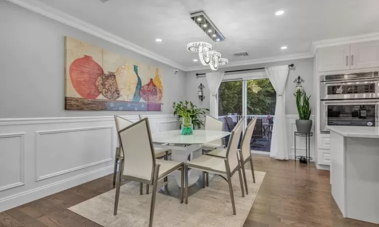 Dining area featuring a notable chandelier, dark hardwood / wood-style flooring, and ornamental molding