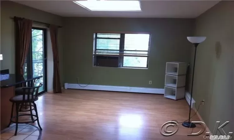 Spare room with a baseboard heating unit, bar, and hardwood / wood-style floors