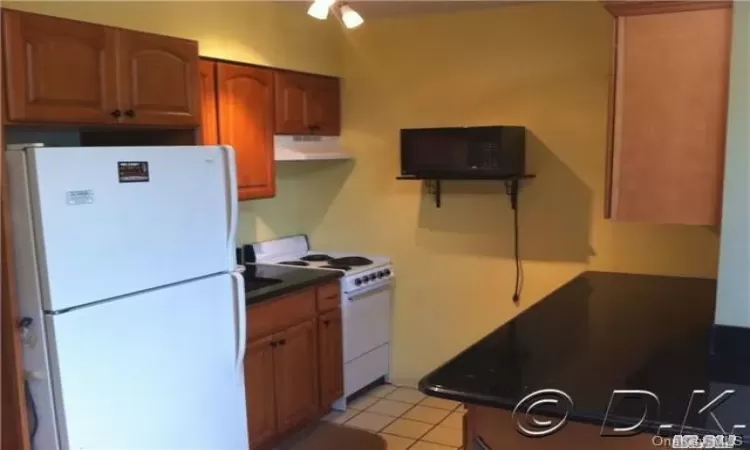 Kitchen featuring light tile patterned floors and white appliances