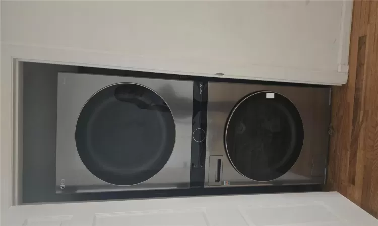 Laundry area with stacked washer and dryer and dark hardwood / wood-style floors