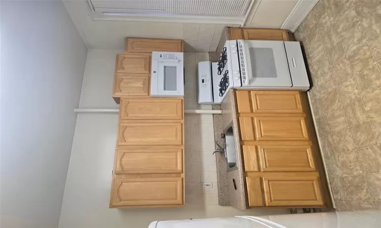 Kitchen featuring range, light brown cabinets, decorative backsplash, sink, and fridge