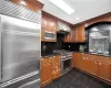 Kitchen with backsplash, range hood, sink, premium appliances, and dark stone counters