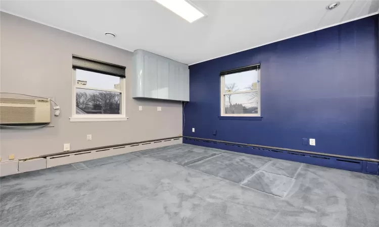 Empty room featuring baseboard heating, a wall mounted AC, and carpet floors