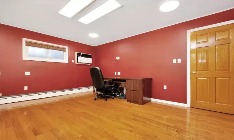 Office space with a baseboard heating unit, a wall unit AC, and light hardwood / wood-style floors