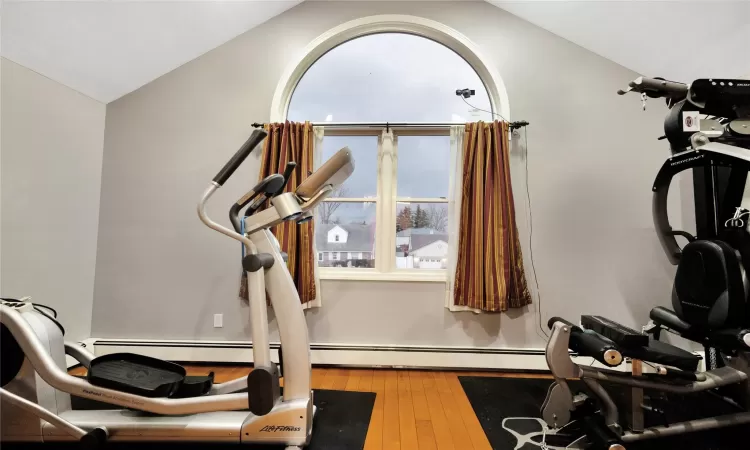 Exercise area featuring vaulted ceiling and hardwood / wood-style floors