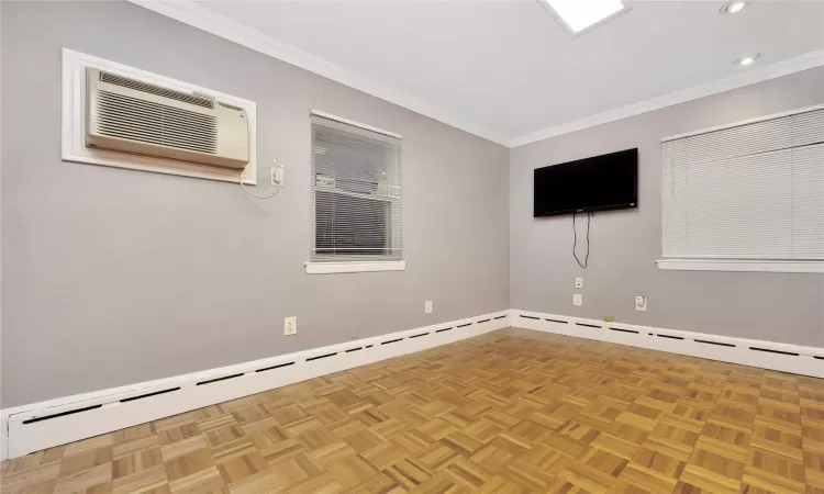 Spare room featuring an AC wall unit, light parquet floors, and crown molding