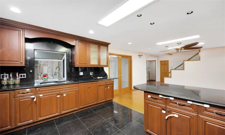 Kitchen with ceiling fan, dark stone countertops, tasteful backsplash, and sink