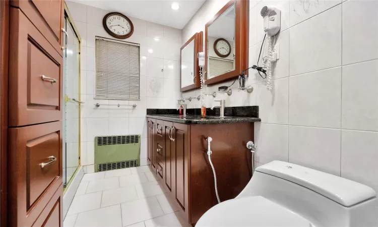 Bathroom with tile walls, toilet, and radiator