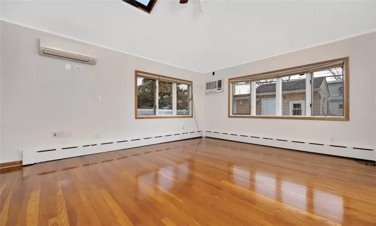 Spare room featuring ornamental molding, hardwood / wood-style flooring, a baseboard radiator, and a wall mounted air conditioner