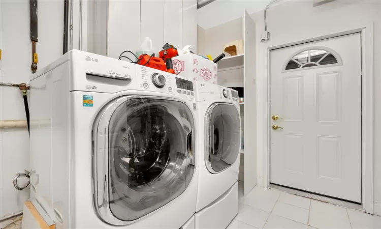 Laundry room featuring light tile patterned flooring and washing machine and clothes dryer